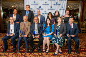 Six award recipients are seated with the person who presented their awards standing behind them.